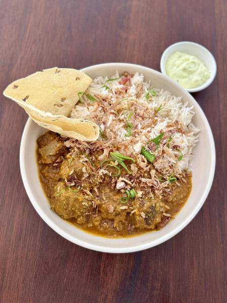 Slow-braised lamb shoulder in a , Nepali spiced curry, served with pumpkin, fluffy rice, crispy papad, and a cooling yogurt sauce